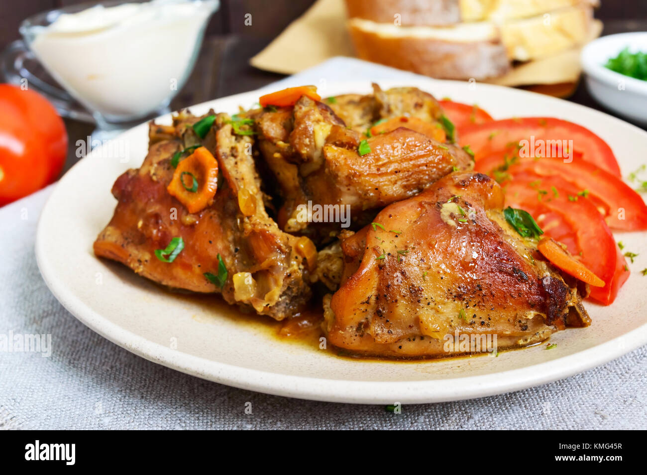 Stewed rabbit pieces with fresh tomato on a ceramic plate on a dark ...