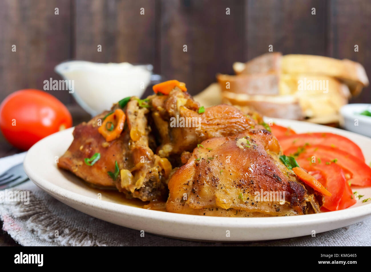 Stewed rabbit pieces with fresh tomato on a ceramic plate on a dark ...