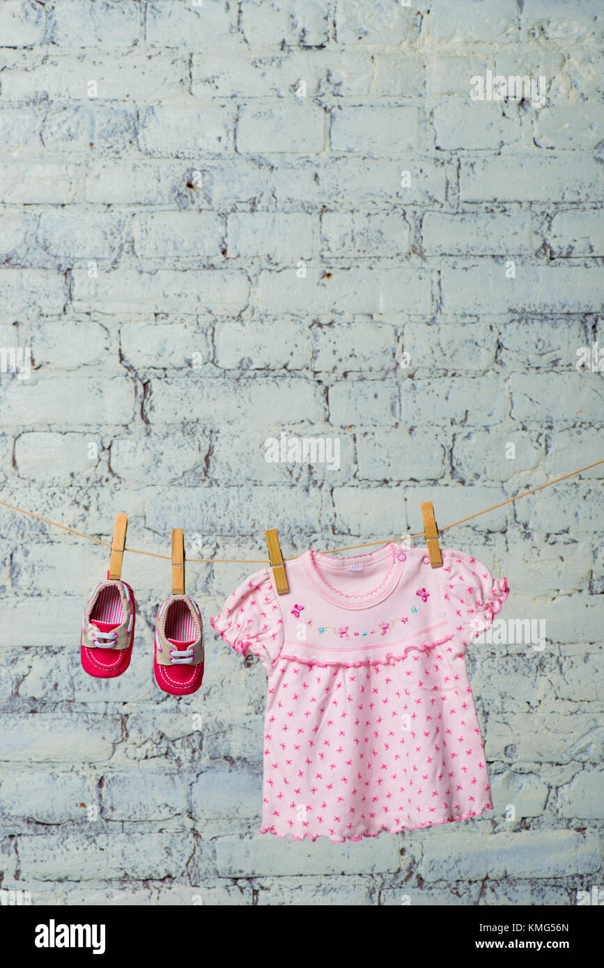 Baby pink dress and red shoes for the girl, dry on a rope against a ...