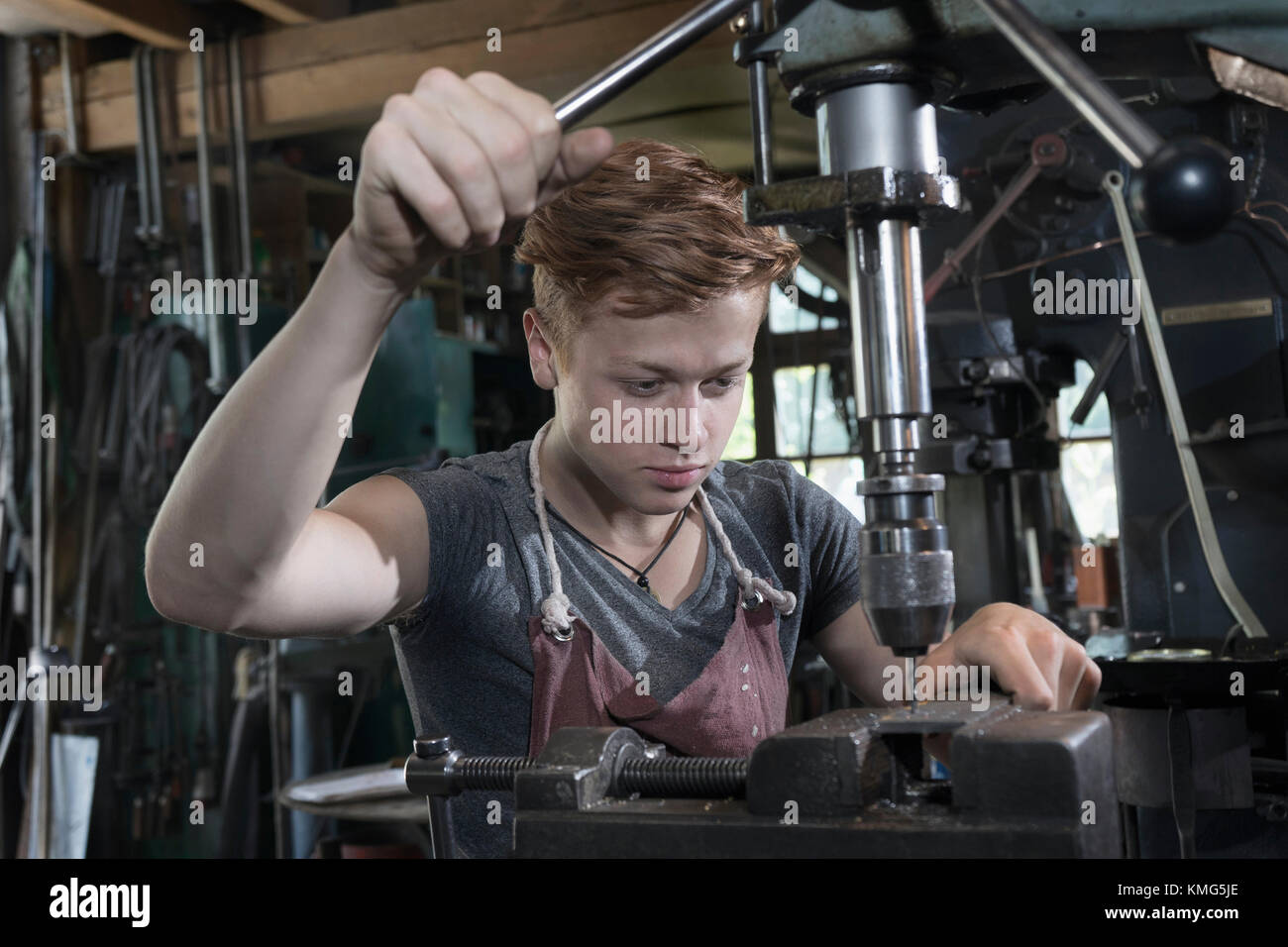 Blacksmith Apprentice Using Drilling Machine At Workshop Stock Photo ...