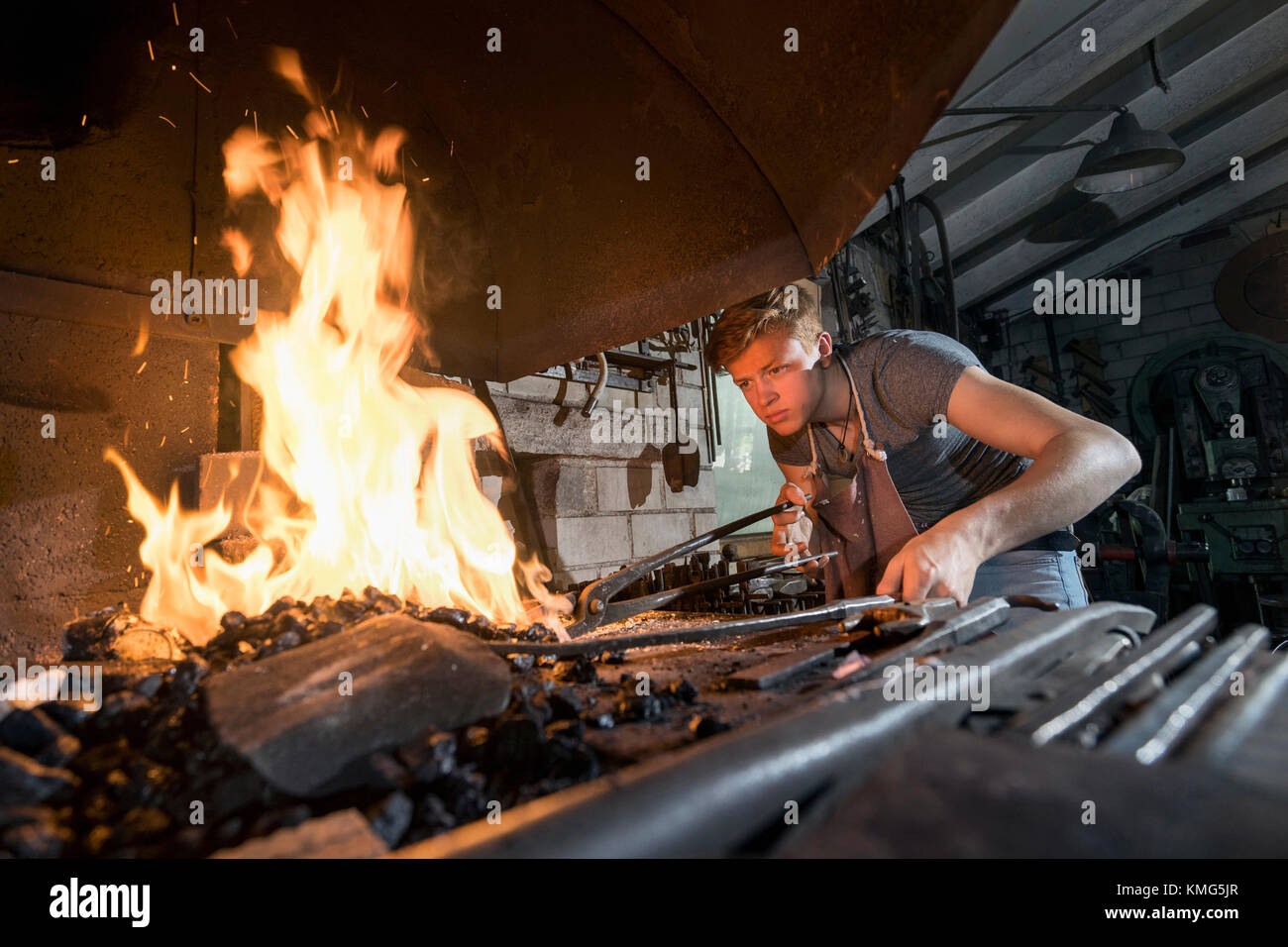 Blacksmith apprentice lightning fire in furnace at workshop Stock Photo