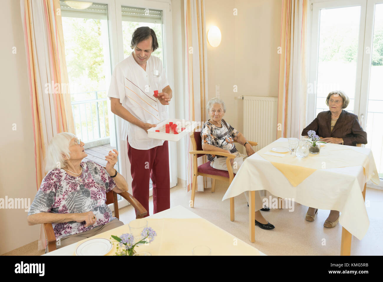Caretaker giving medicine to senior woman at rest home Stock Photo