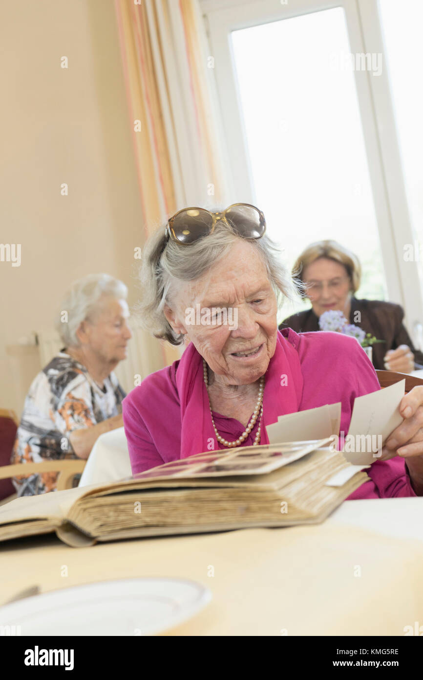 Senior woman watching photo album in rest home Stock Photo