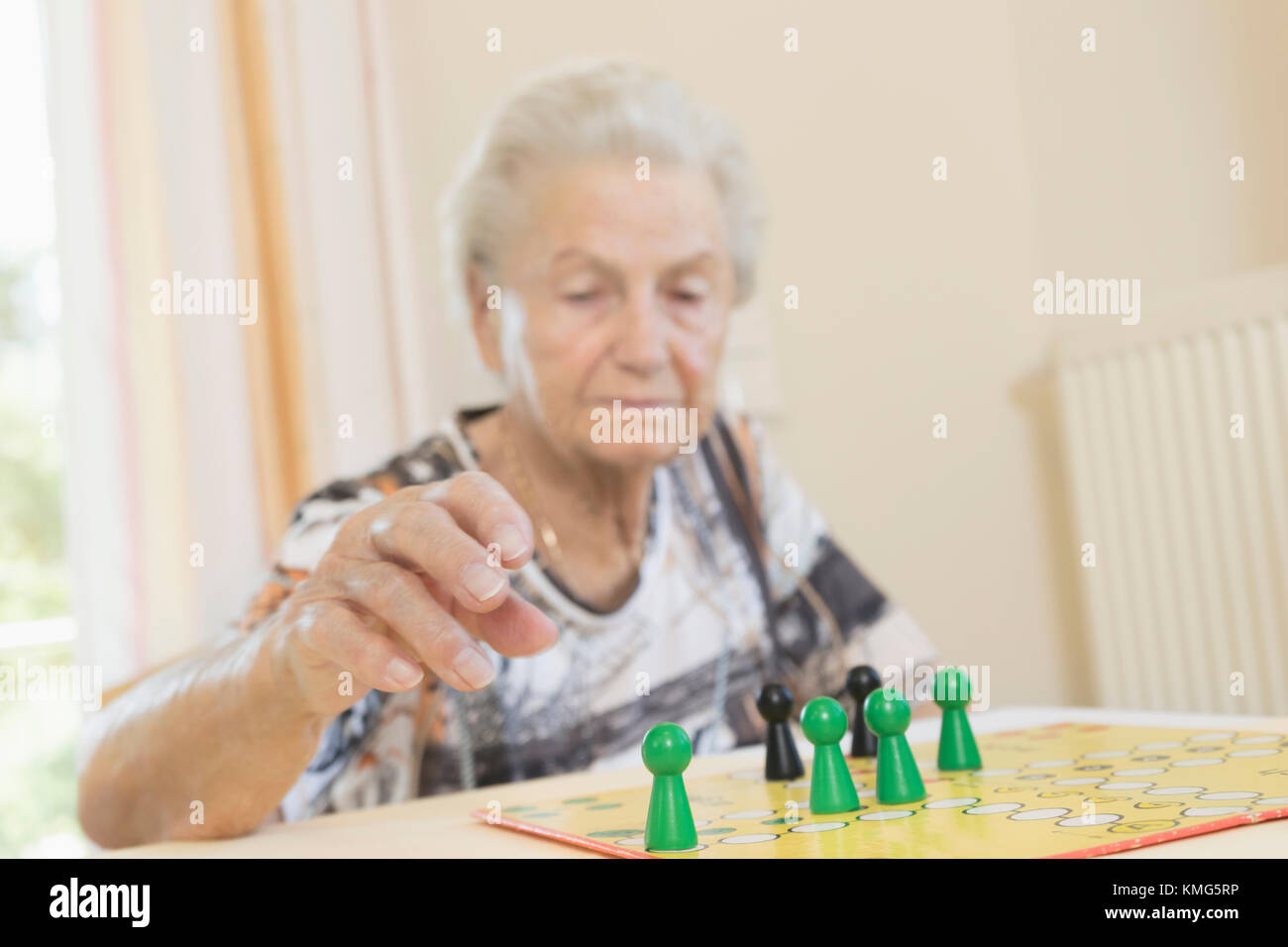 Senior woman playing board game in rest home Stock Photo