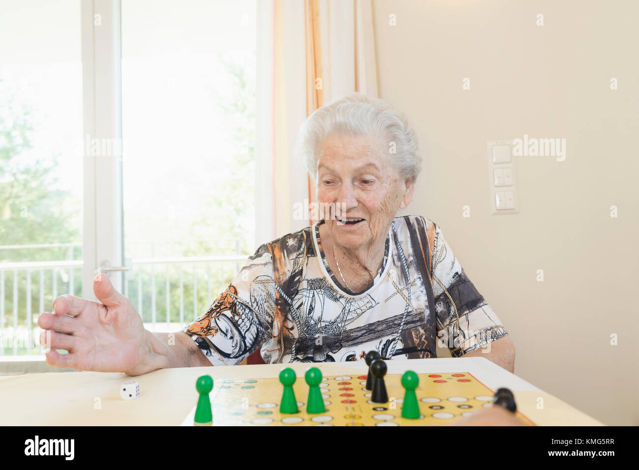 Senior woman playing board game in rest home Stock Photo