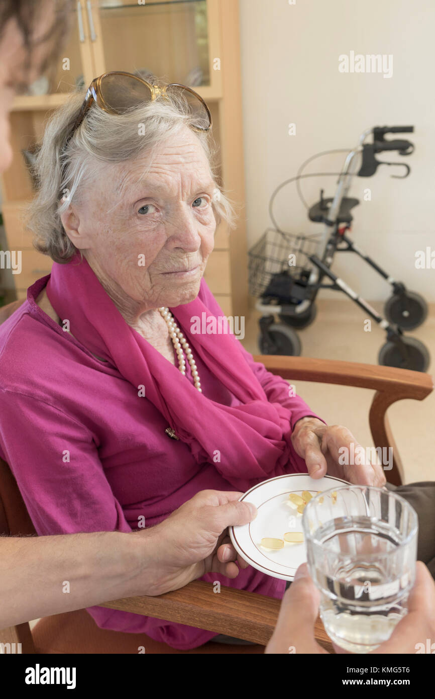 Caretaker giving medicine to senior woman at home Stock Photo