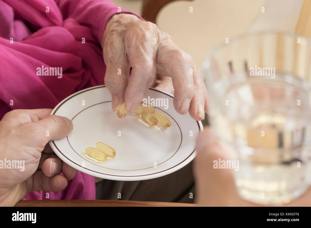 Caretaker giving medicine to senior woman at rest home Stock Photo