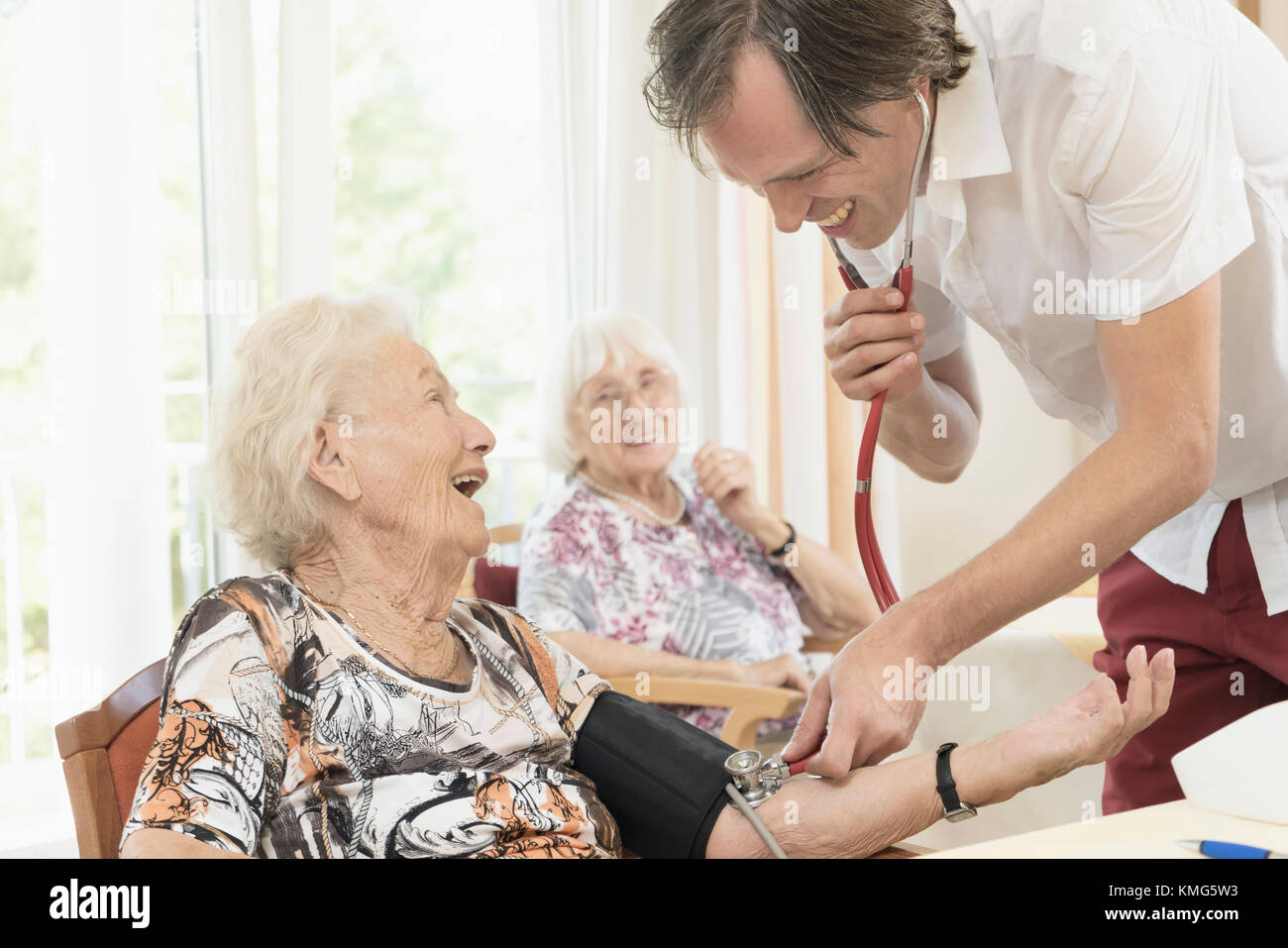 Caretaker checking blood pressure of senior woman in rest home Stock Photo