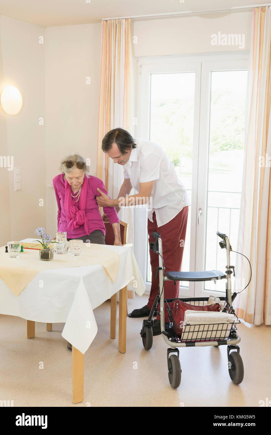 Caretaker helping senior woman using wheeled walker Stock Photo