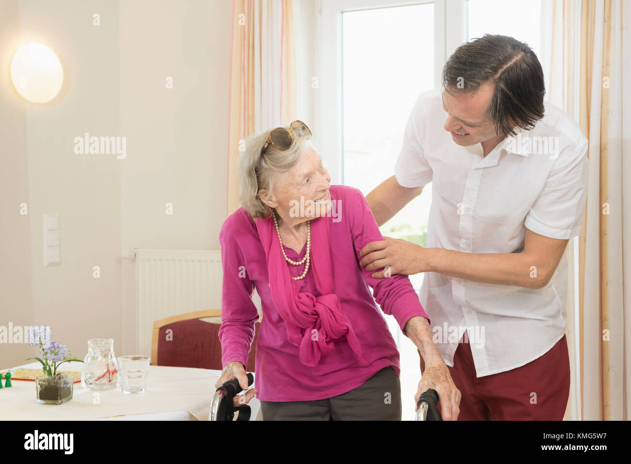 Caretaker helping senior woman using walker Stock Photo