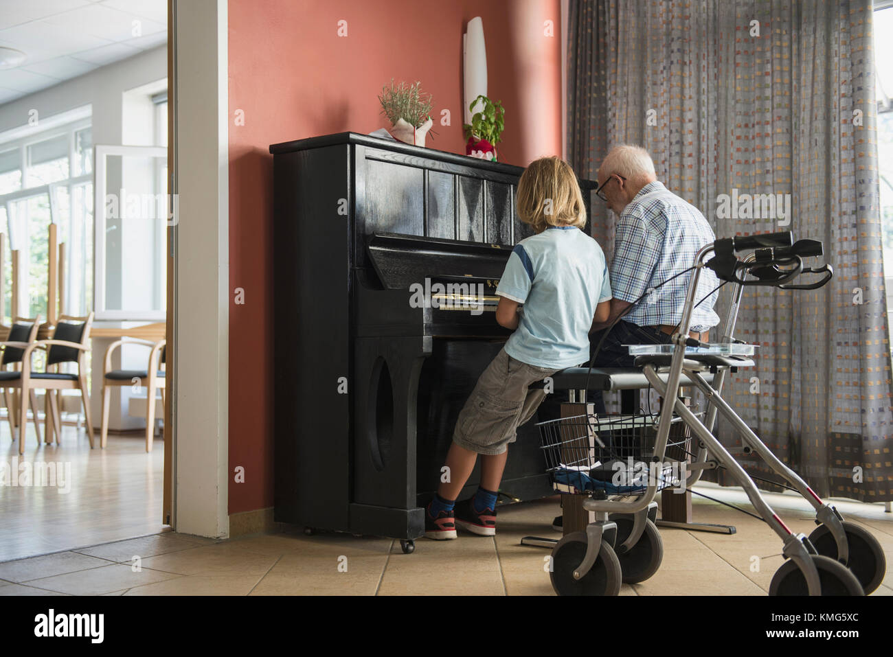 Grandfather teaching piano instrument to his grandson Stock Photo