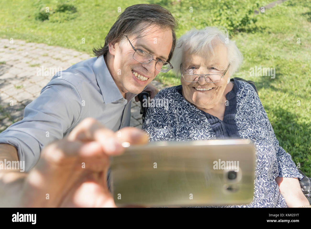 Son taking selfie with disabled mother on wheelchair Stock Photo