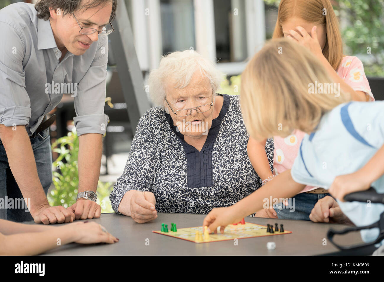 Senior woman with family enjoying board game in rest home Stock Photo