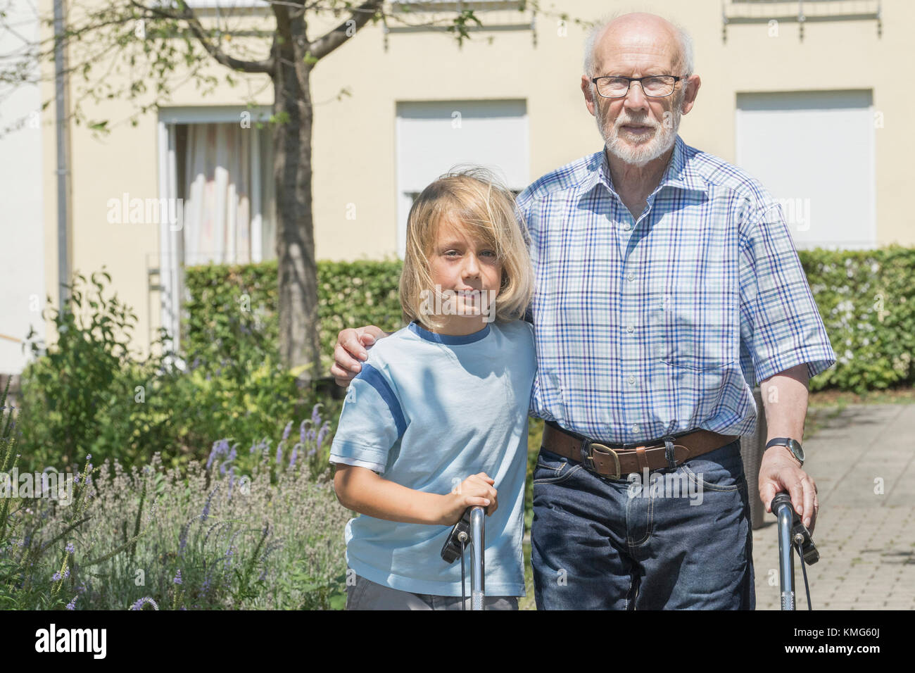 Boy helping grandfather with mobility walker at rest home park Stock Photo