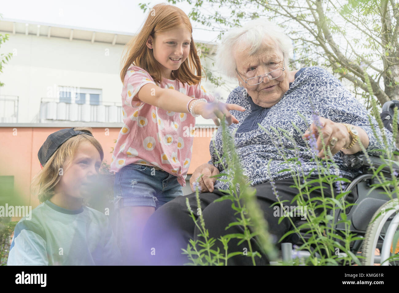 Senior woman on wheelchair with grandchildren at rest home park Stock Photo