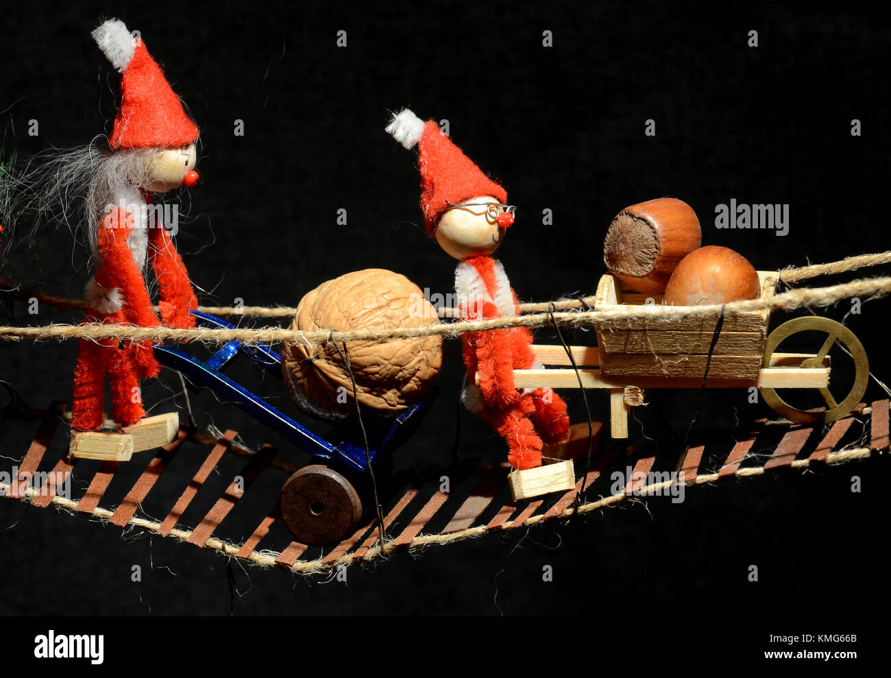 Pixie gang vrosses a wobbly bridge wih look carried odn dollies and wheelbar. Stock Photo