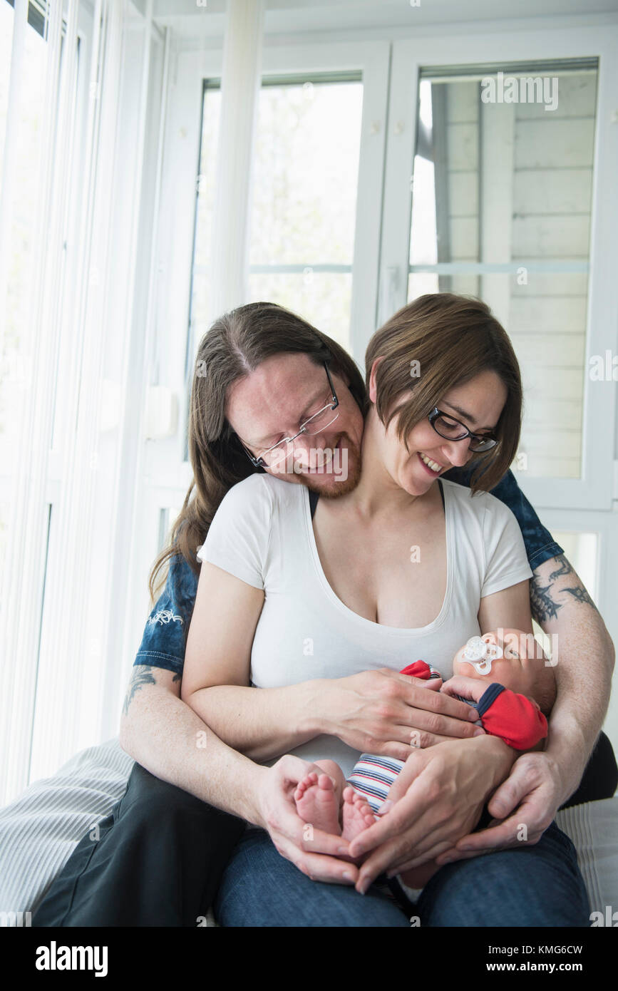 Parents cuddling with newborn baby boy at home Stock Photo Alamy