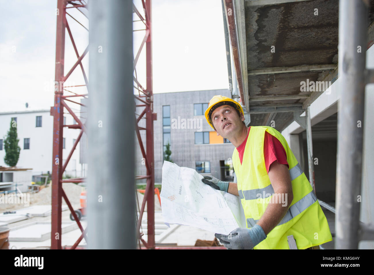 Construction worker holding blueprint at construction site Stock Photo ...