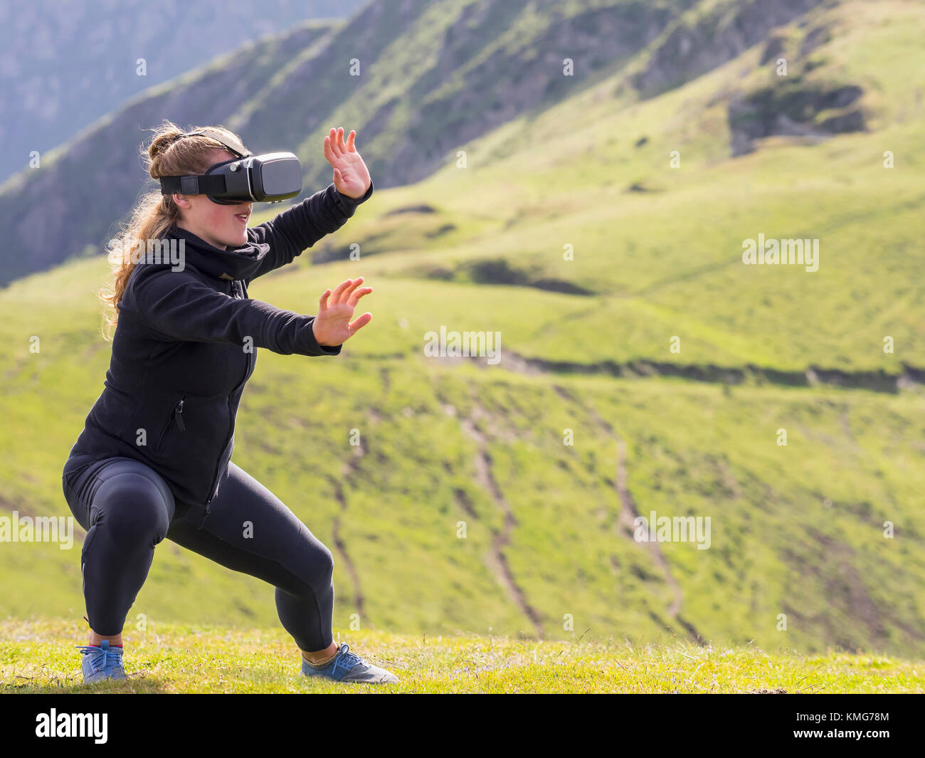 Woman practicing Tai Chi moves with virtual reality glasses on mountain Stock Photo