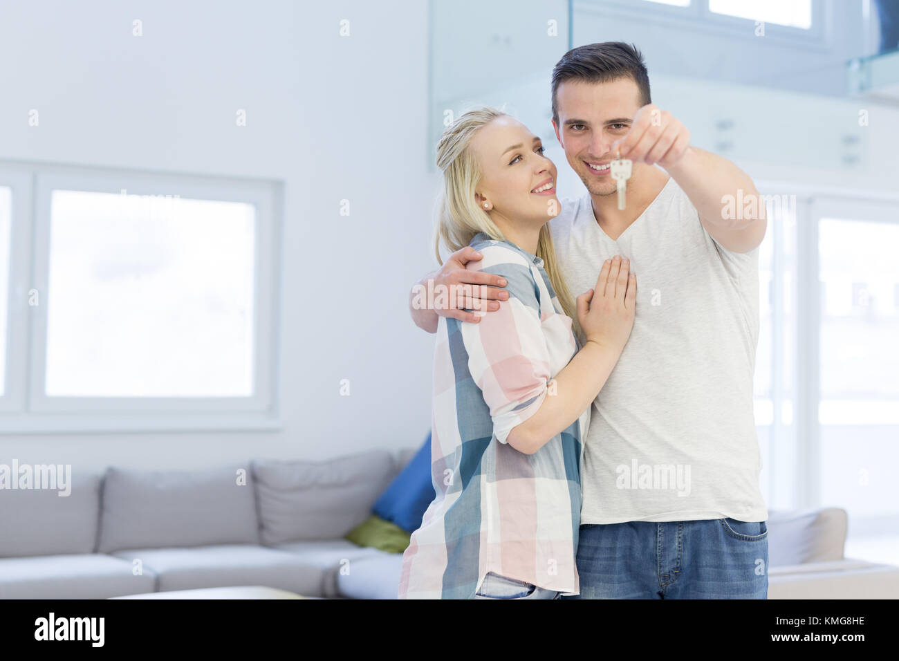 Happy smiling young couple hugging while showing a keys of their new ...