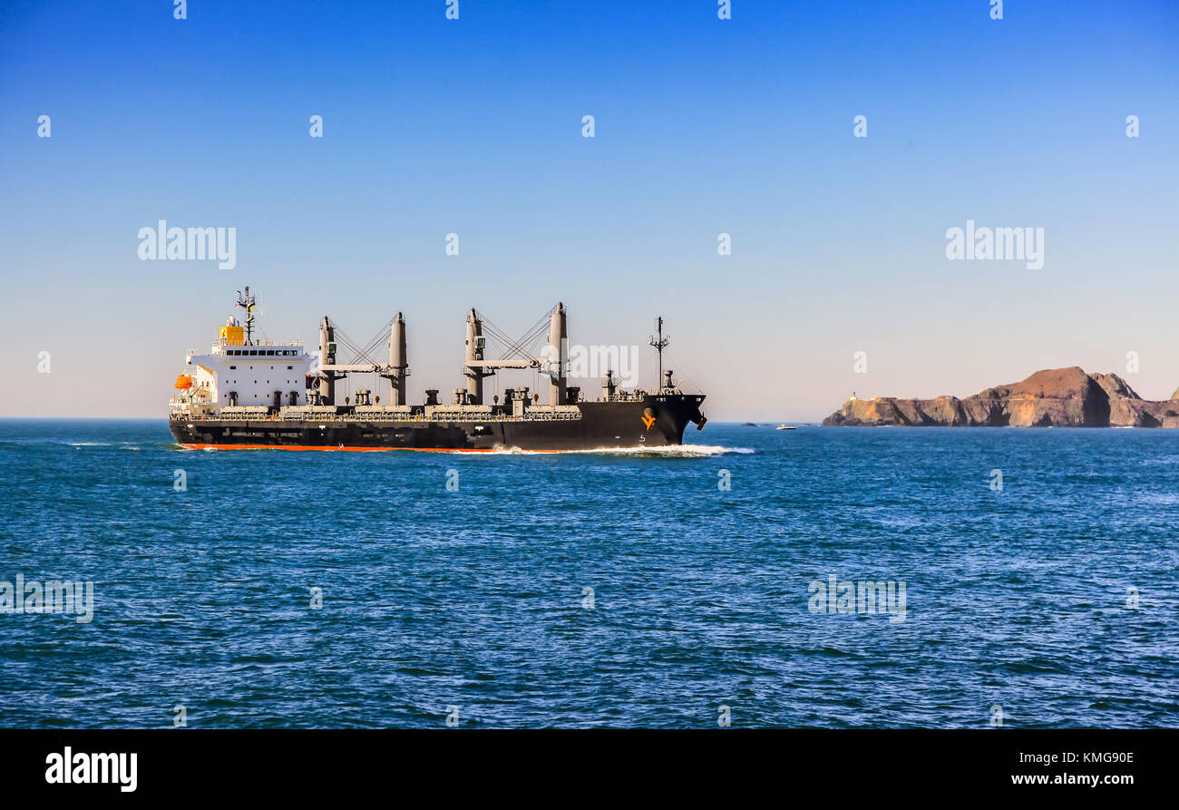 Cargo ship sailing to port on sunny day Stock Photo - Alamy