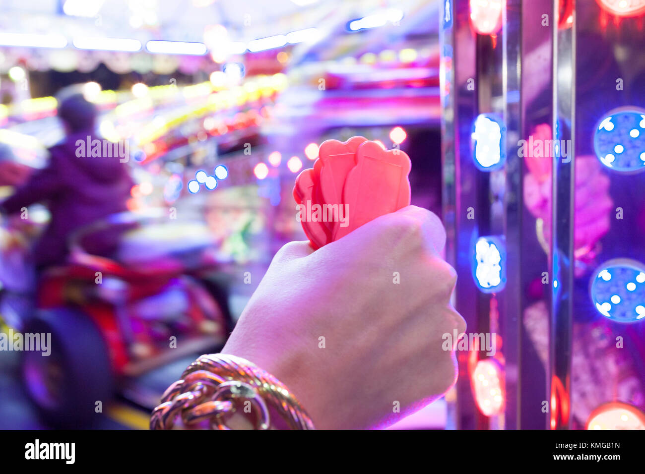 Woman hand with a fistfull of chips for fairground ride childrens cars track. Night scene Stock Photo