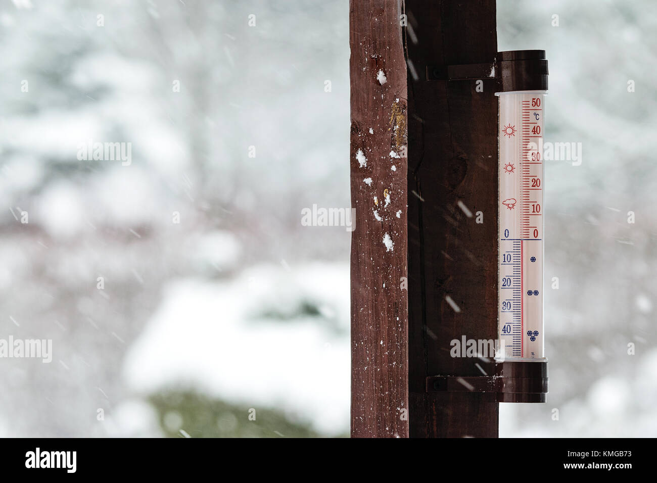 Concept image of winter coming - thermometer outside the house indicates below zero and it is snowing heavily. Stock Photo