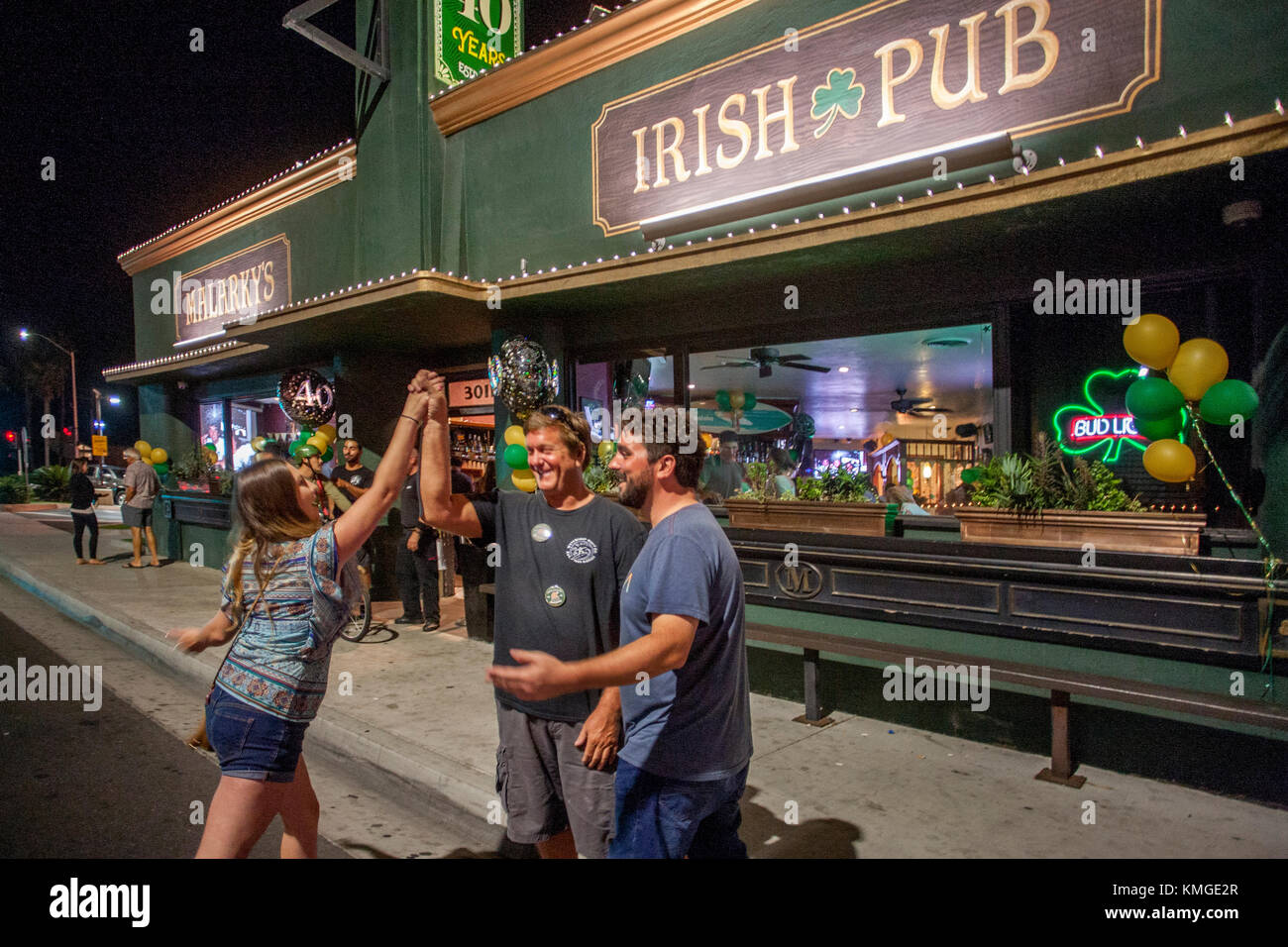 Am exuberant young woman high fives a man outside an Irish bar in Newport Beach, CA. Stock Photo