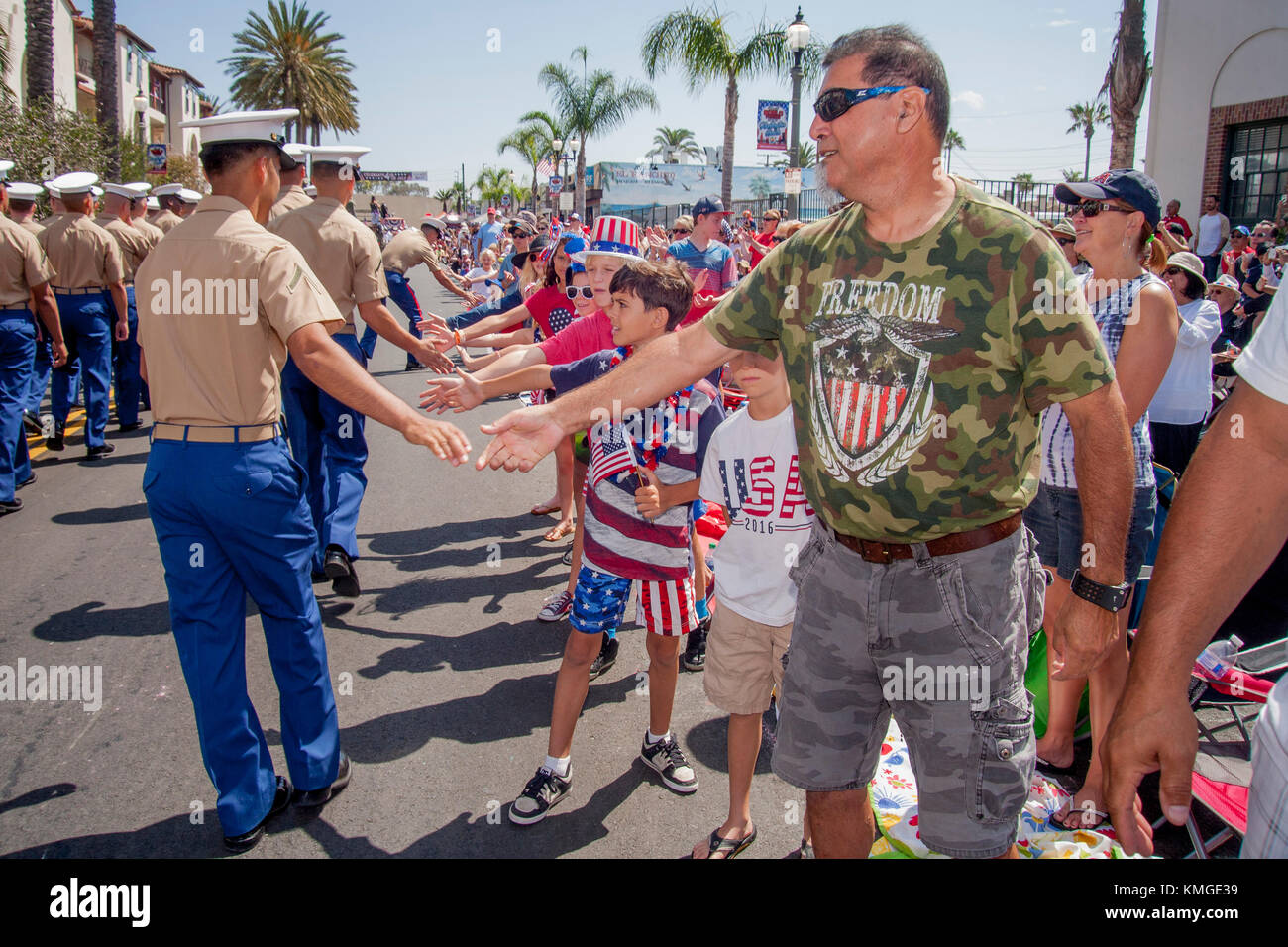 Uniformed US Marine participants in a July 4th parade in Huntington Beach, CA, receive patriotic handshakes from spectators. Note T shirt. Stock Photo