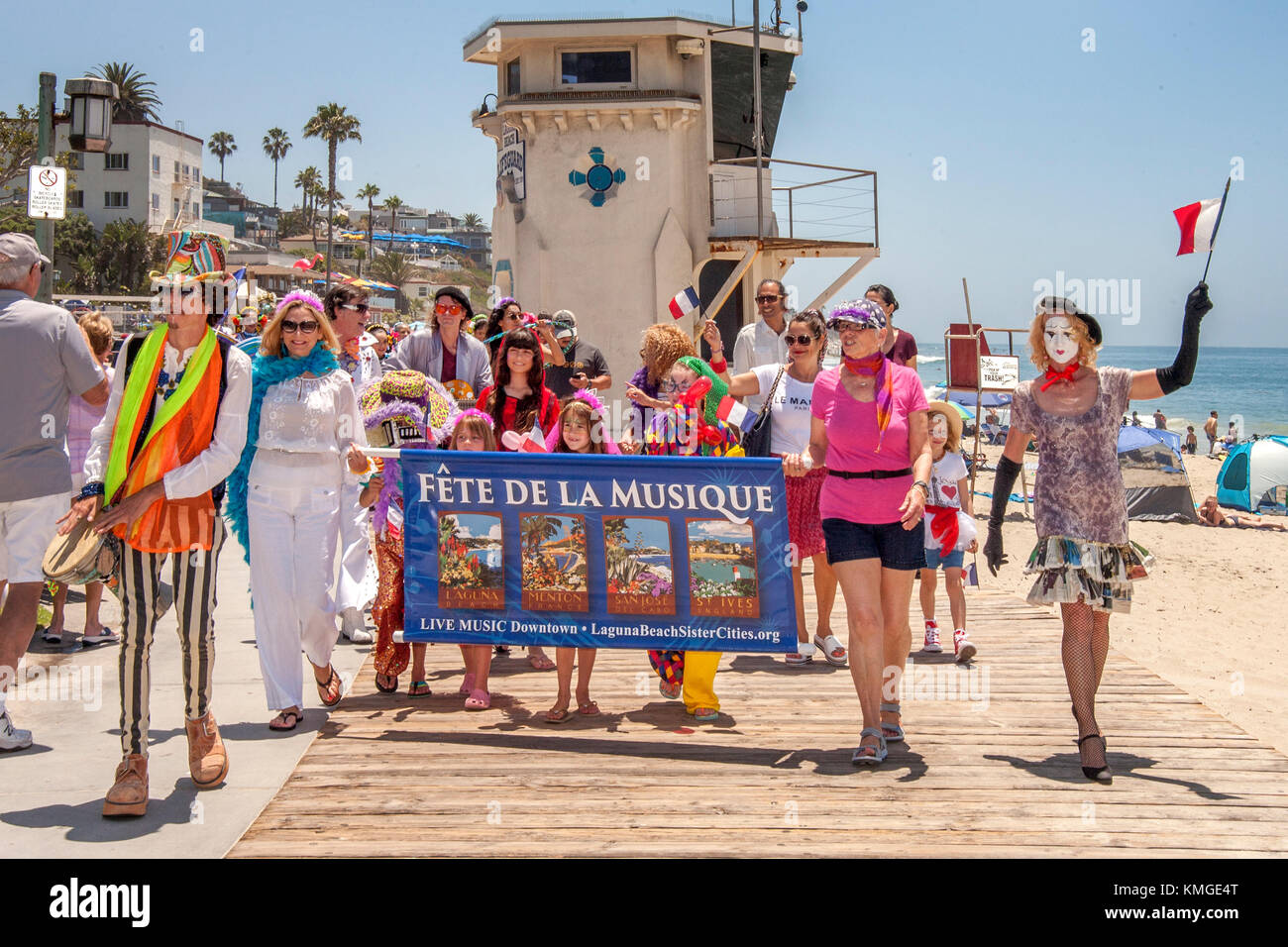 The 'Fete de La Musique' music festival in Laguna Beach, CA, begins with a beach parade accompanied by a mime with a French flag in front of the beach's famous Lifeguard Tower. Stock Photo