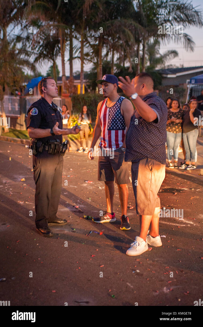 A Costa Mesa, CA, policeman writes a a citation after apprehending a Hispanic local man for use of illegal fireworks on July 4th. Stock Photo