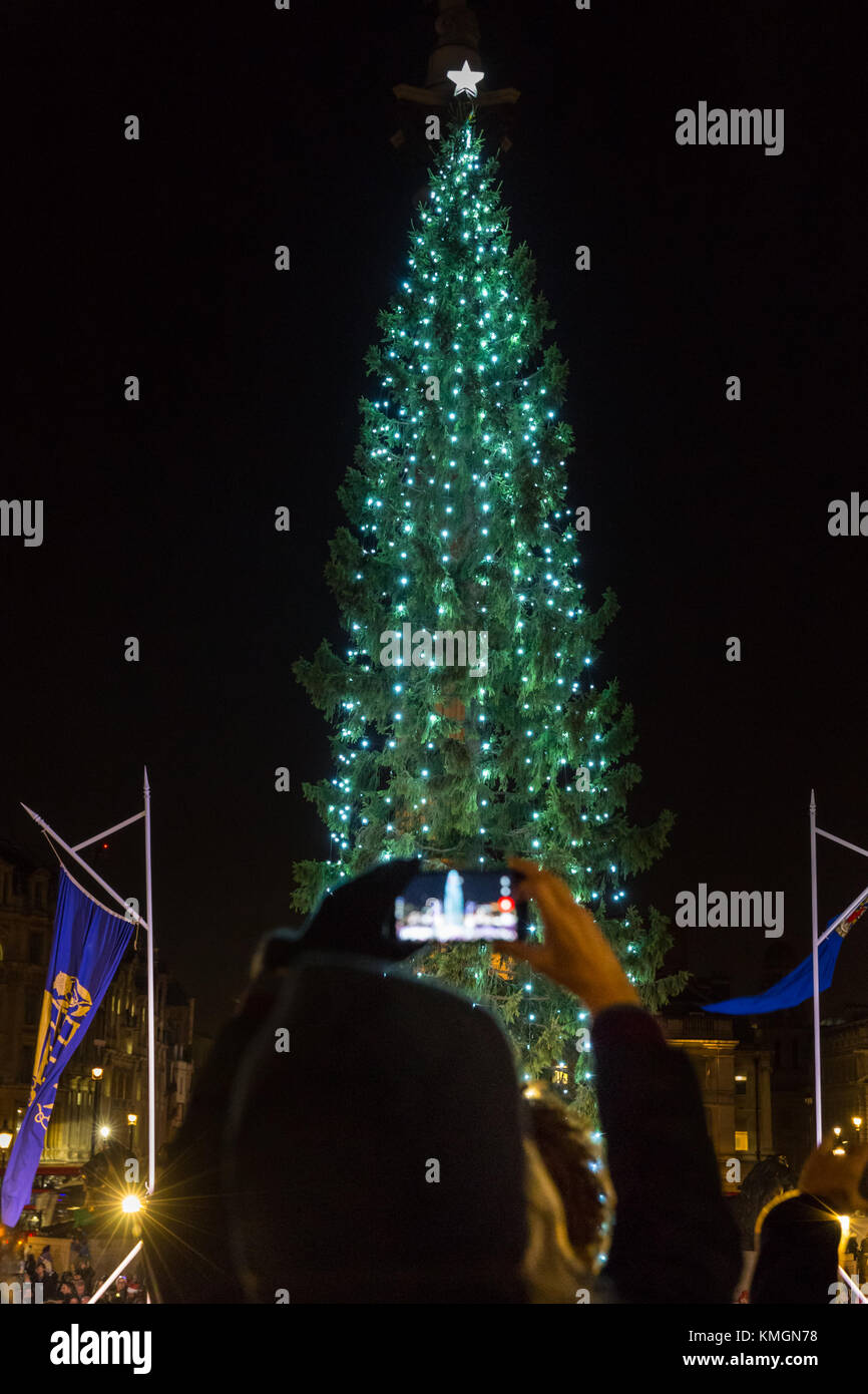 Trafalgar Square, London, 7th Dec 2017. A woman takes snaps of the illumunated tree. The annual Trafalgar Square Christmas Tree lighting ceremony takes place in the square, with tourists and Londoners watching the official switch on, as well as carols and choral singing in festive atmosphere. The Trafalgar Square Christmas tree is hand picked and donated to the people of Britain by the city of Oslo, Norway each year since 1947, and 2017 is its 70th anniversary. Stock Photo