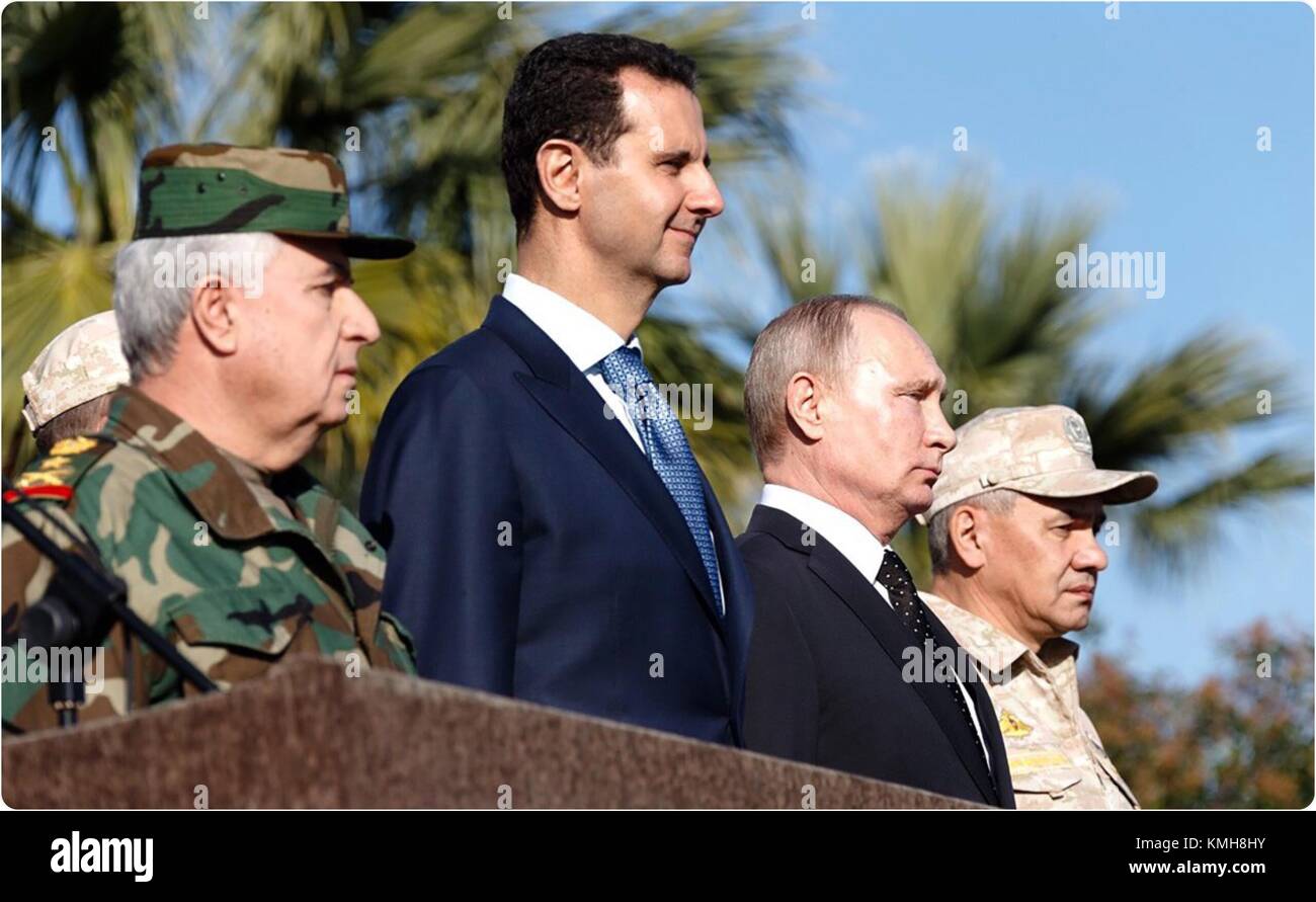 Damascus, Syria. 11th Dec, 2017. Syrian President Bashar al-Assad (2nd L, Front) and his Russian counterpart Vladimir Putin (2nd R) view a military parade in the Russian-run Hmeimim Air Base in the coastal city of Latakia, Syria, on Dec. 11, 2017. Syrian President Bashar al-Assad met with his Russian counterpart Vladimir Putin in Syria on Monday, the presidential media office reported. During Putin's visit, he ordered his defense minister to prepare for withdrawing the Russian forces, according to the report. Credit: Syrian Presidency/Xinhua/Alamy Live News Stock Photo