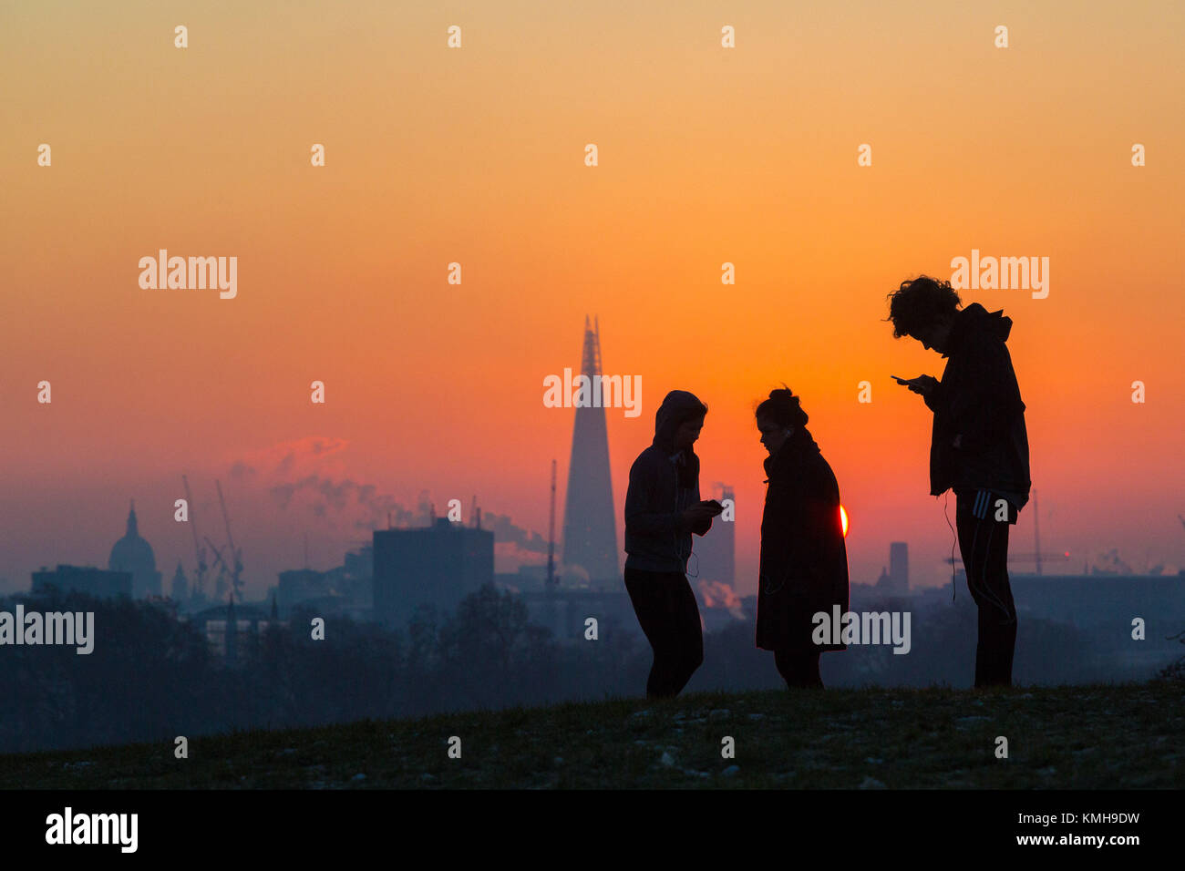 London, UK. 12th Dec, 2017. London, December 12 2017. Early morning walkers in silhouette against the city's skyline as the sun rises on a clear very cold morning in London, seen from Primrose Hill in Camden. Credit: Paul Davey/Alamy Live News Stock Photo