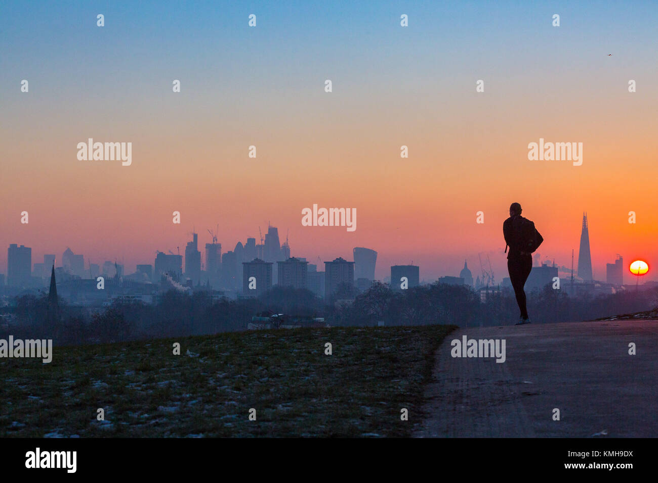 London, UK. 12th Dec, 2017. London, December 12 2017. A jogger's silhouette is seen against the skyline as the sun rises on a clear very cold morning in London, seen from Primrose Hill in Camden. Credit: Paul Davey/Alamy Live News Stock Photo