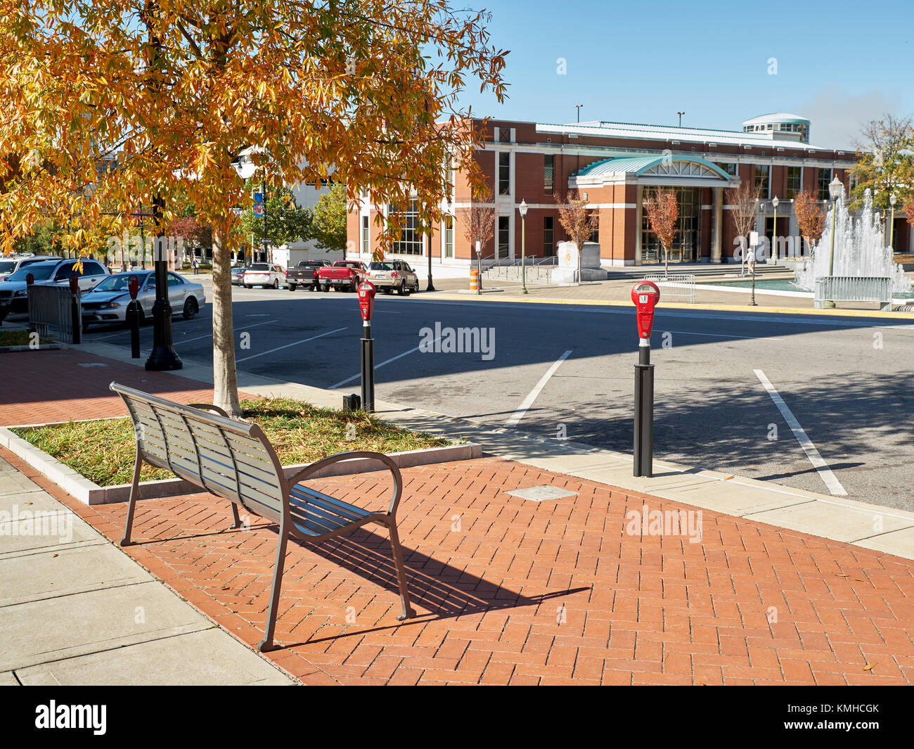 Empty parking spaces and a metal bench on a street in the downtown district of a city. Stock Photo