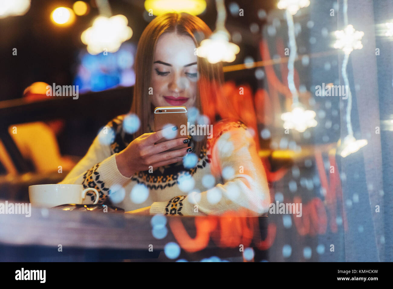 Young beautiful woman sitting in cafe, drinking coffee. Magic snowfall effect. Christmas, new year, Valentines day, winter holidays concept. The photo Stock Photo