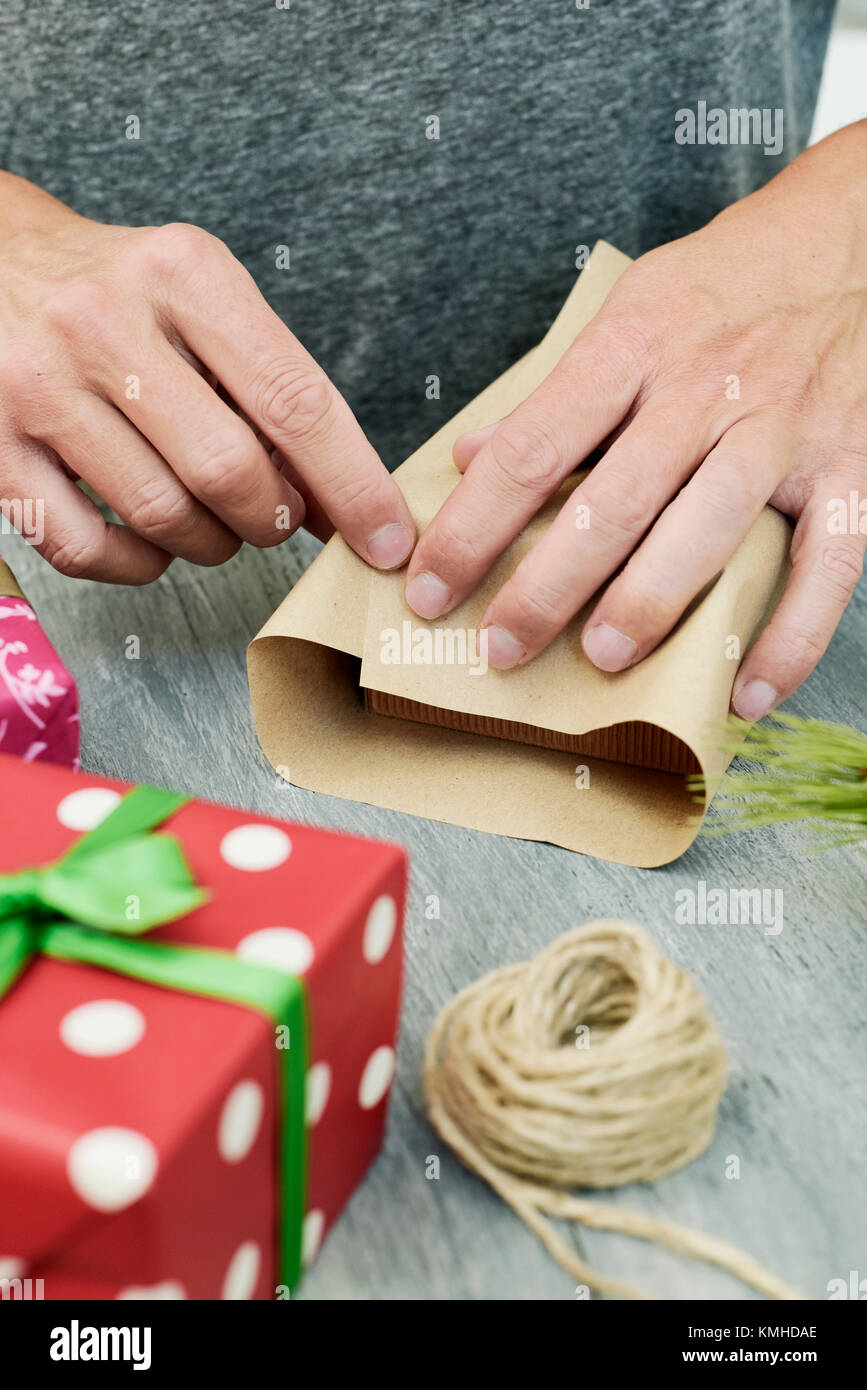 https://c8.alamy.com/comp/KMHDAE/closeup-of-a-young-caucasian-man-wrapping-a-gift-on-a-gray-rustic-KMHDAE.jpg