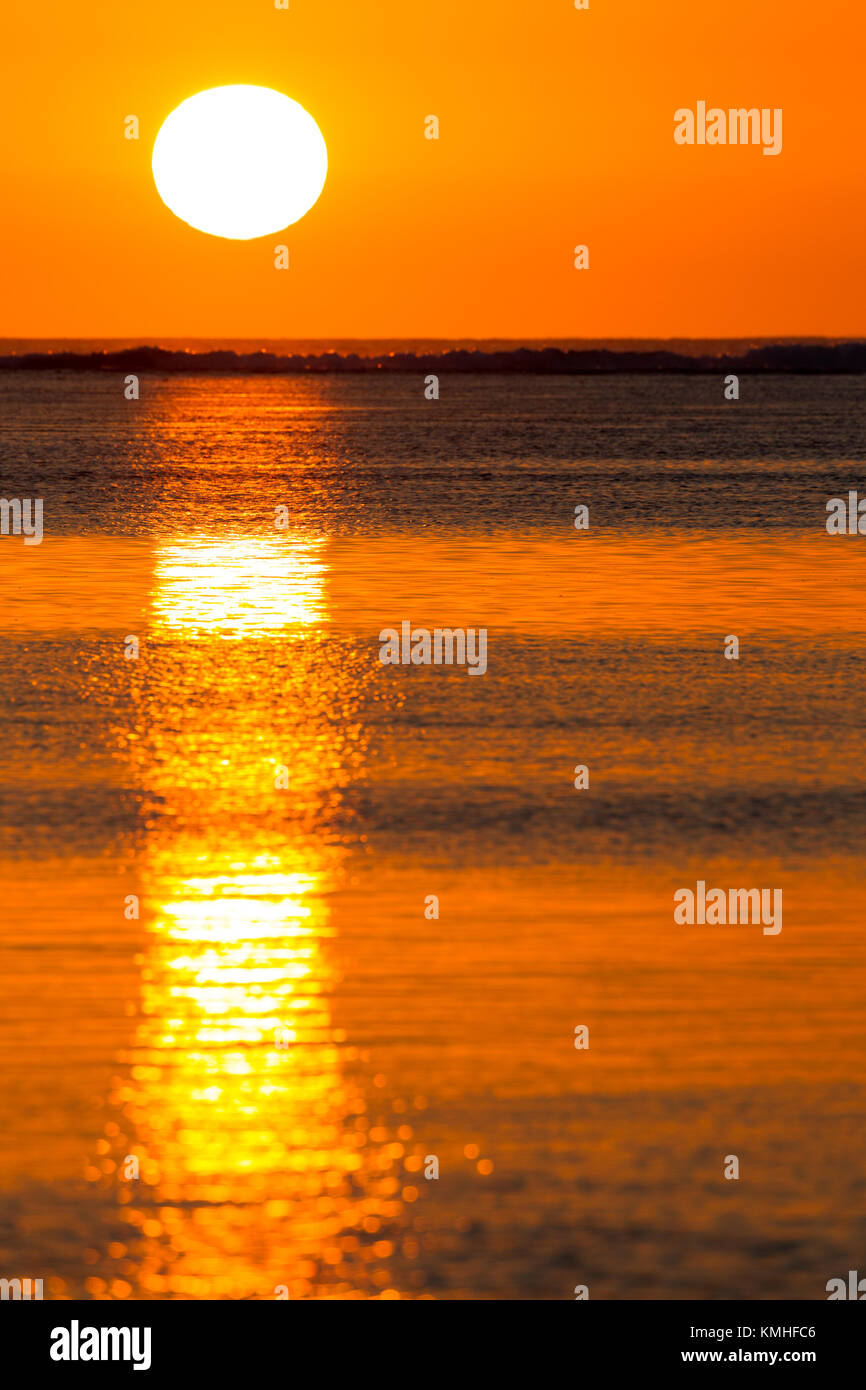 The golden light of the setting sun reflecting in the calm water of the lagoon at Le Morne in Mauritius, Africa. Stock Photo