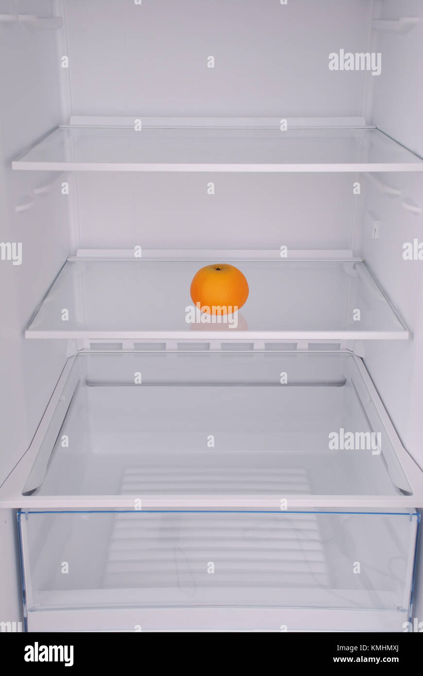 One mandarin in open empty refrigerator. Weight loss diet concept Stock Photo Alamy
