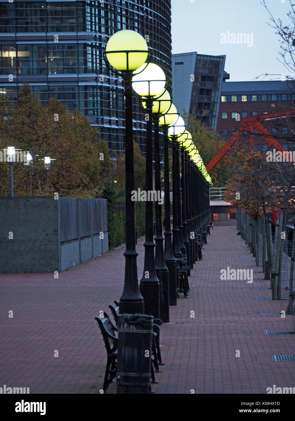 a receding line of globe street lights shining brightly at dusk on the ...