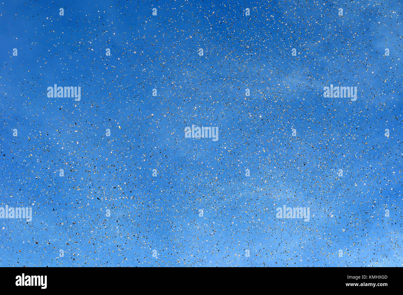 falling golden confetti in the city festival on blue sky background ...
