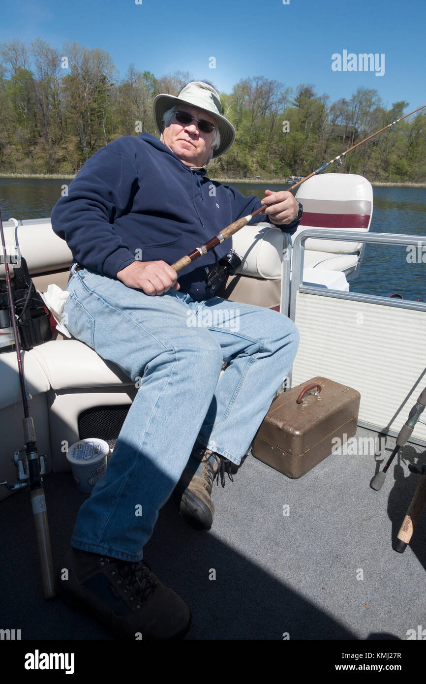 Dapper senior retired fisherman relaxing in a pontoon boat hoping a fish will jump into the boat. On the Gull lake chain. Nisswa Minnesota MN USA Stock Photo