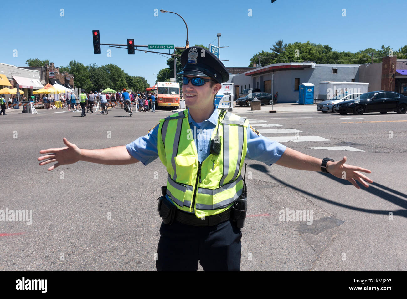 Policeman wearing a florescent safety vest directing traffic at Grand Old Day festivities. St Paul Minnesota MN USA Stock Photo