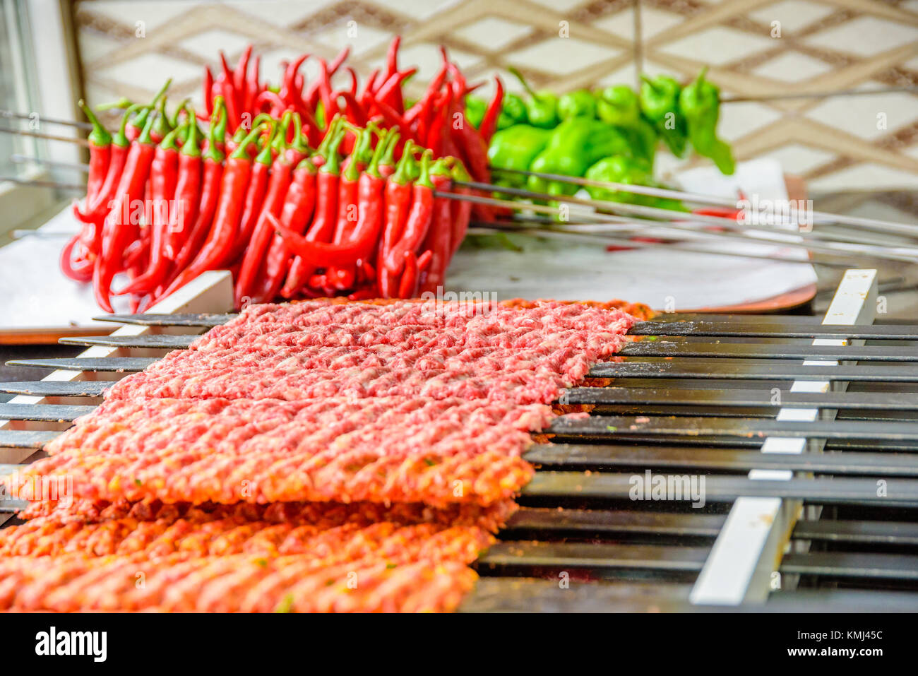 Several Adana Kebab skewers lined up waiting to be cooked and served