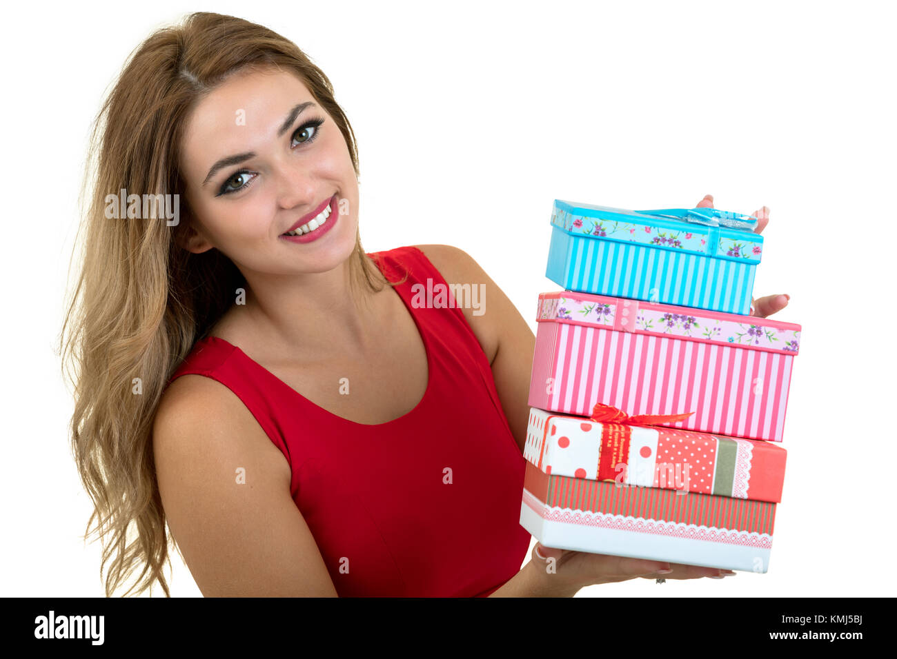Portrait of a smiling pretty girl holding stack of gift boxes isolated ...