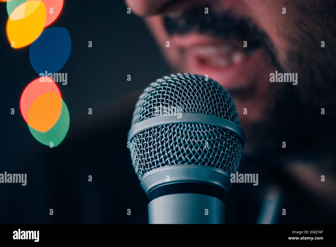 Man sings karaoke in a bar at night with festive bokeh light effect, selective focus Stock Photo