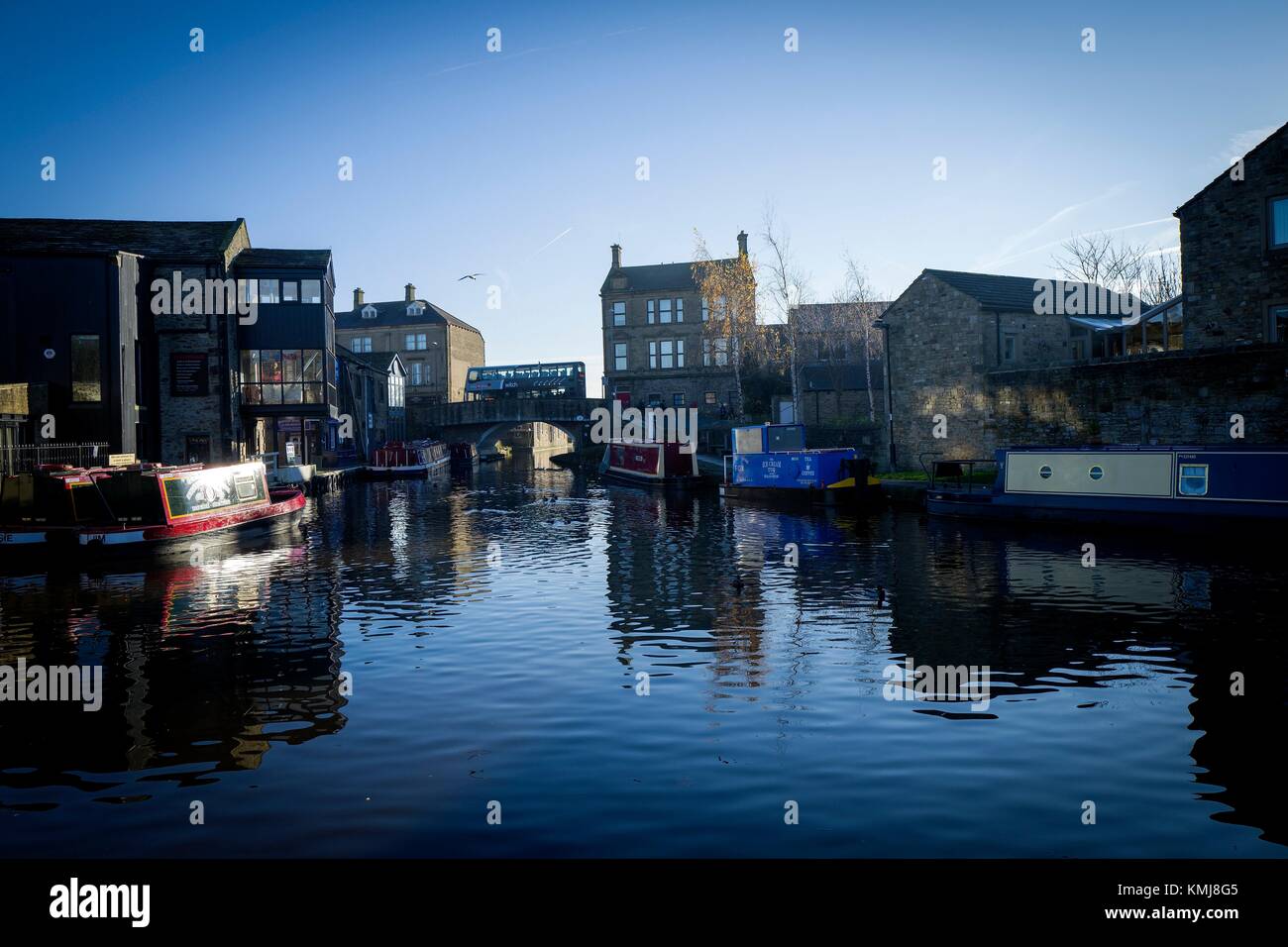 View of canal with boat and houses in the early morning with blue sky. Skipton, North Yorkshire