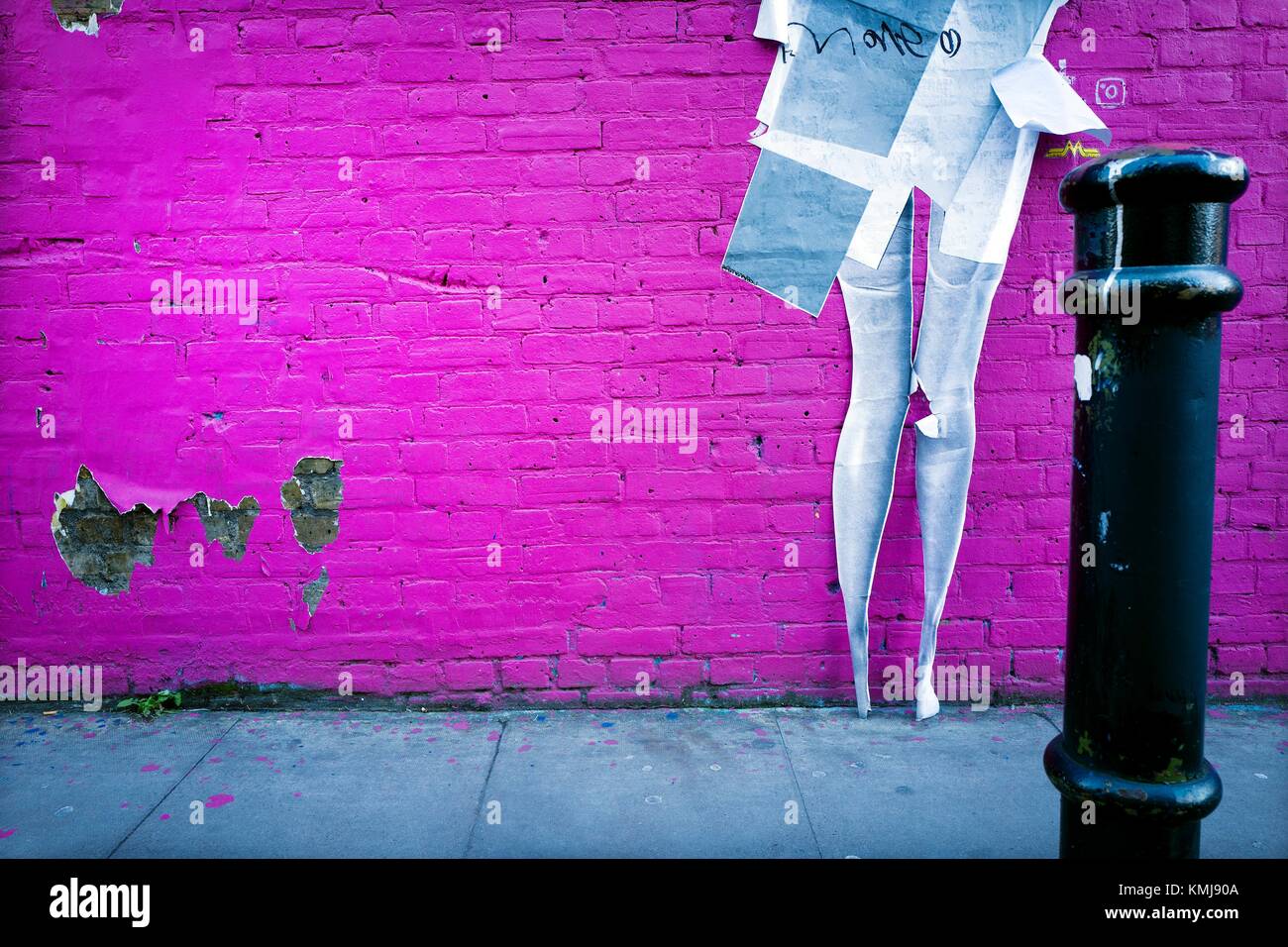 Pared pintada color fucsia con un graffiti de las piernas de una mujer en una calle. Hamburg St., East End, London, UK, Europa. Stock Photo