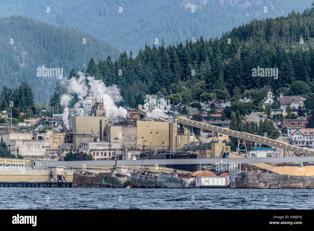 Concrete hulks from World War II form a floating breakwater in front of the paper mill (now closed) and historic Townsite in Powell River, BC (2017). Stock Photo
